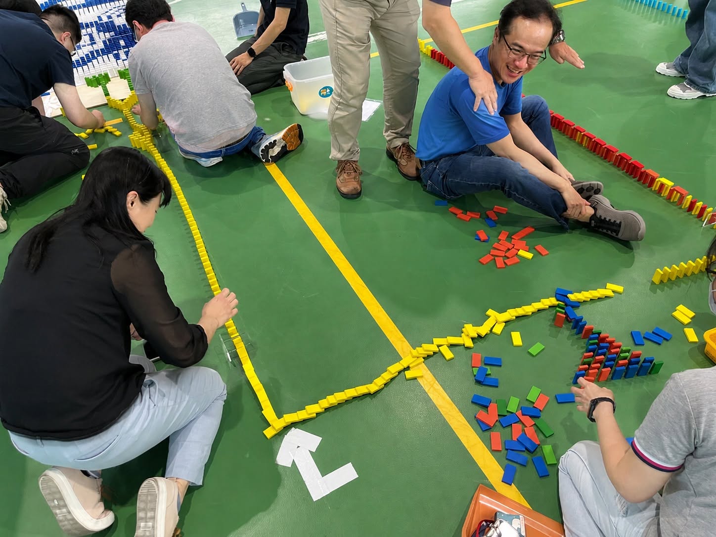 瑞昱半導體同仁分工排列黃色與多色骨牌，在體育館地板上串接不同方向的骨牌路線。